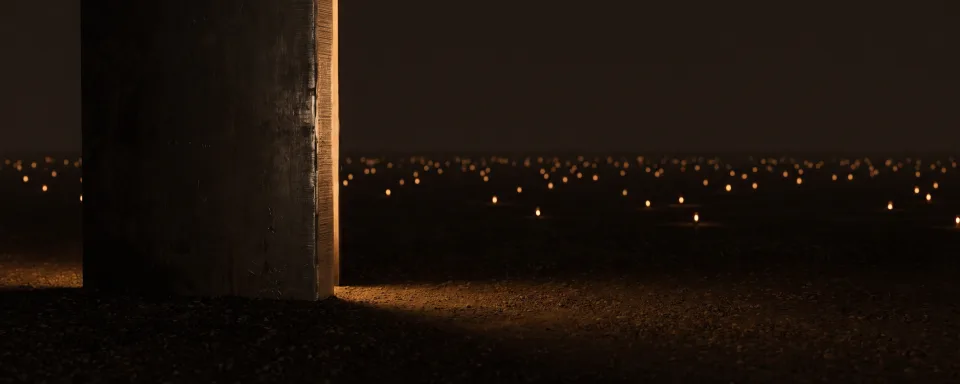 A single enormous slab of dark metal filling the left of the frame with one amber rim light along its edge, and behind it a wide dark plain scattered with hundreds of tiny amber pinpoints, every one dwarfed by the slab.